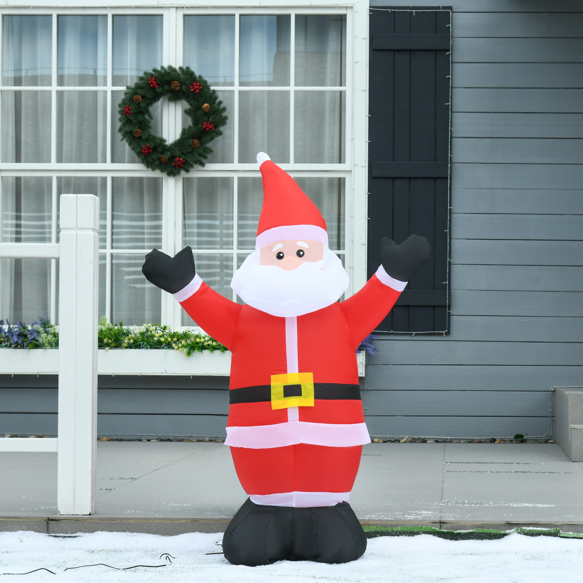 Inflatable Santa Claus decoration in front of a house with a wreath on the door.