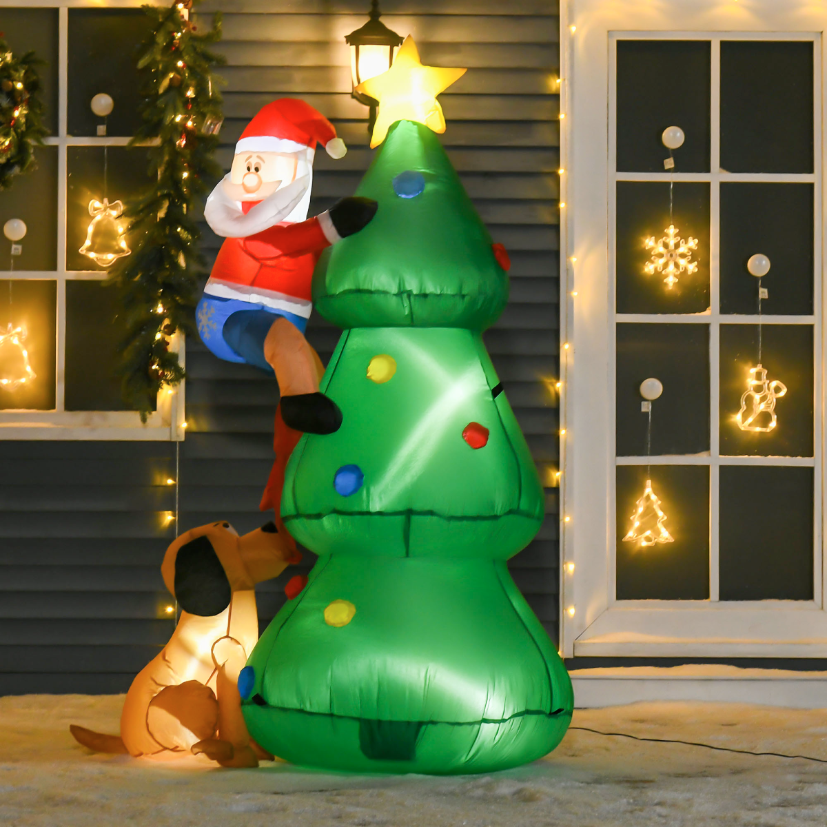 Inflatable Christmas scene with Santa climbing a tree, dog below, and lights on windows.