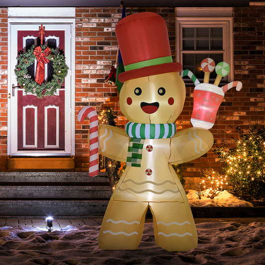 Inflatable gingerbread man decoration holding a cup in front of a brick house with Christmas decorations.