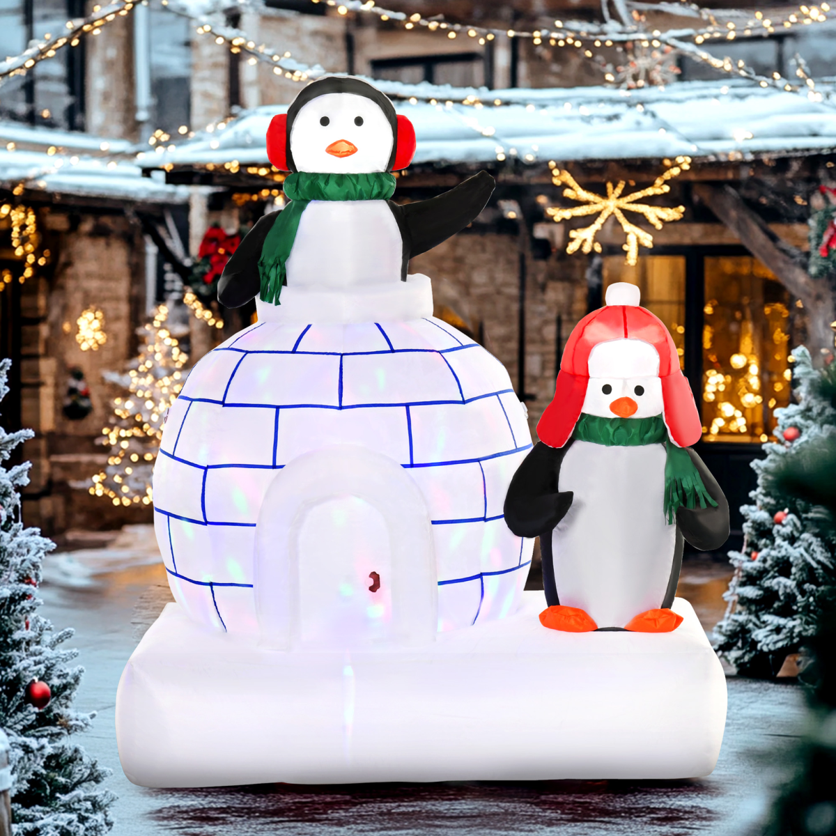 Inflatable penguins with an igloo in a festive outdoor setting with Christmas lights and decorations.