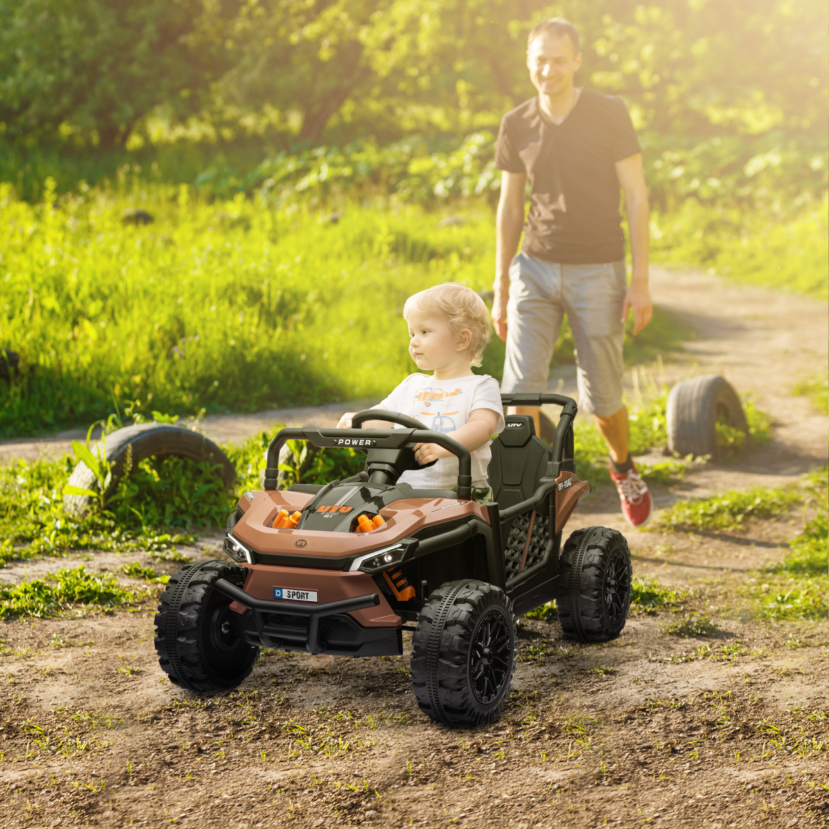 Child in a toy off-road vehicle with a man walking behind in a natural setting
