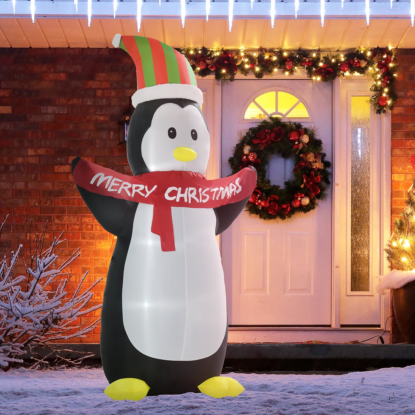 Inflatable penguin with a 'Merry Christmas' scarf in front of a decorated house.